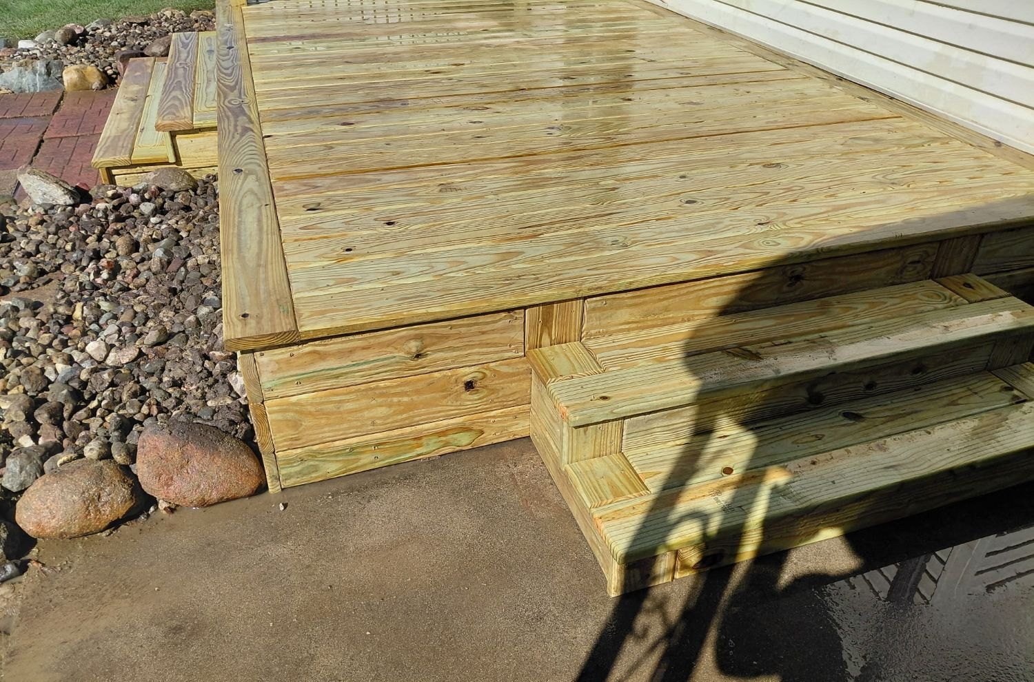 Box steps from the deck down to the concrete pad, with a mitered deck corner above