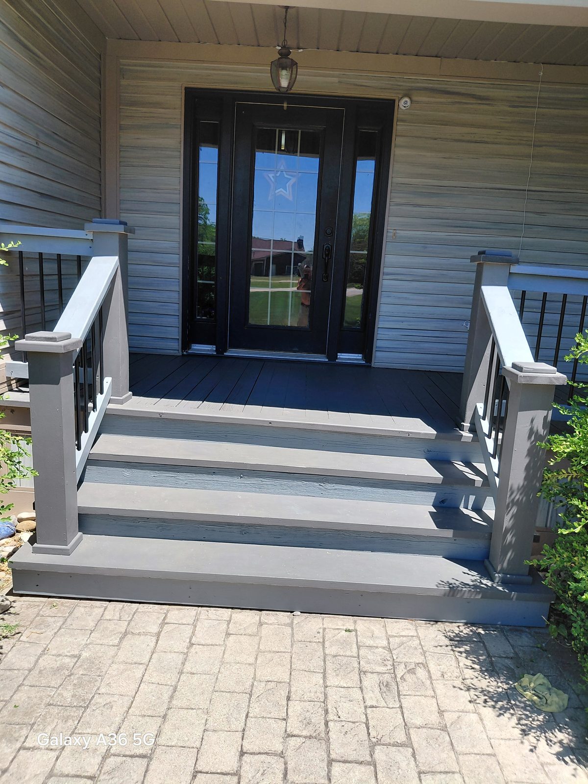 Front porch steps after repainting in a fresh gray finish with black balusters